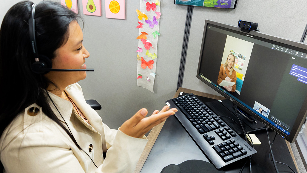 Woman sitting at a computer and talking to another woman via virtual meeting